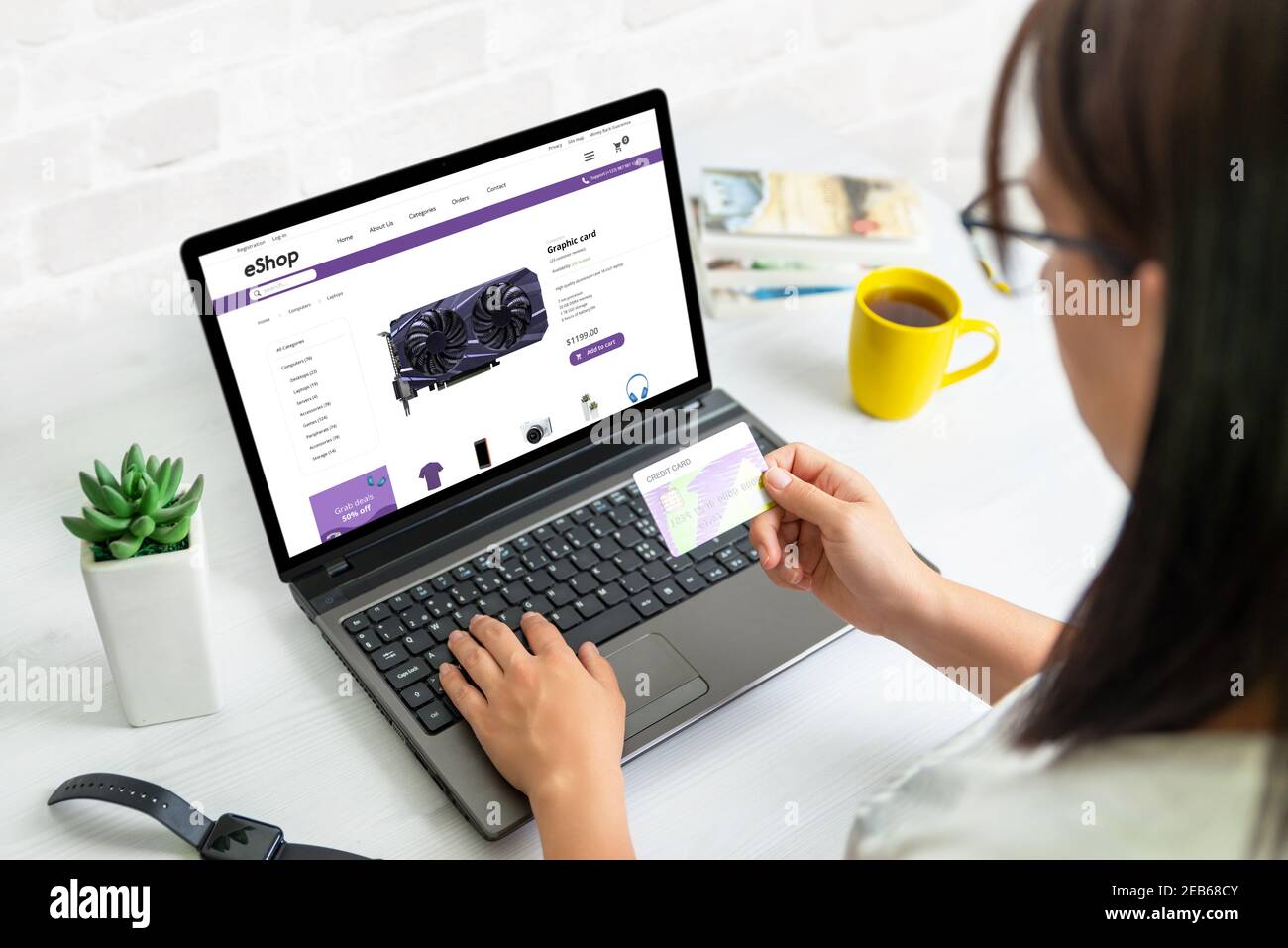 Acquisto di una scheda grafica online concetto. La ragazza tiene una carta di credito e acquista attraverso il sito web ecommerce Foto Stock