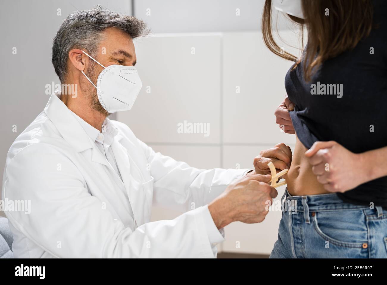 Medico che misura il grasso corporeo utilizzando il calibro del grasso nella clinica Foto Stock