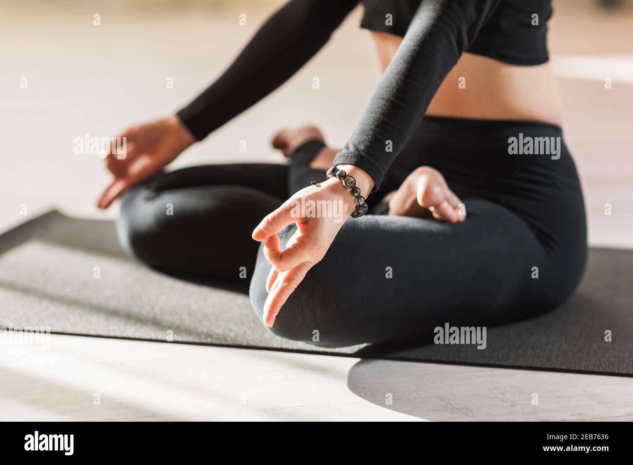 Una donna nello sport nero che pratica lo yoga, è impegnata nella meditazione in posizione di loto ed esegue il simbolo della mudra del mento con le mani, close-u Foto Stock