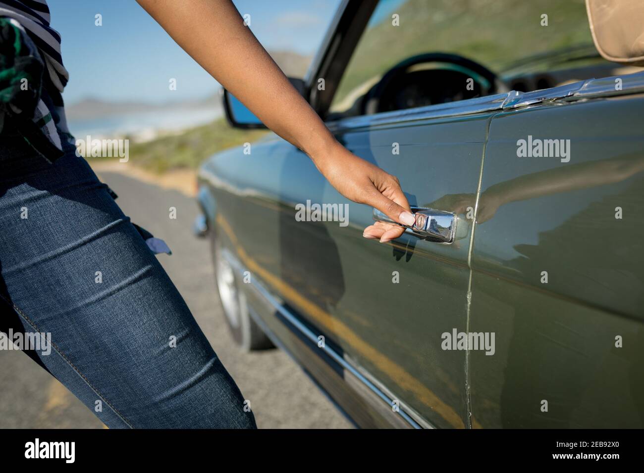 Misto gara donna in giornata di sole che entra nella vettura convertibile Foto Stock