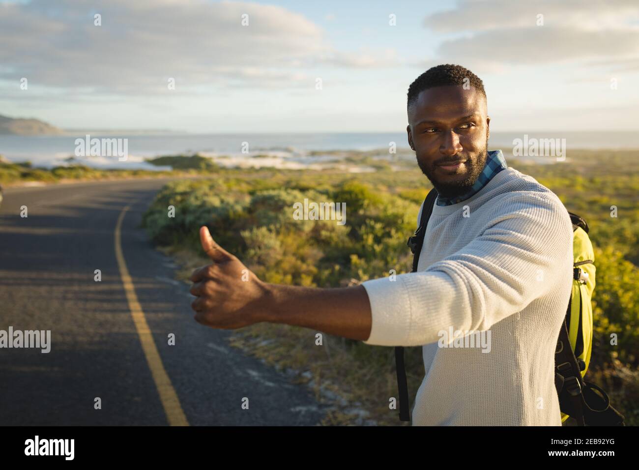 Uomo afro-americano in piedi dalla strada e hitchtrekking Foto Stock