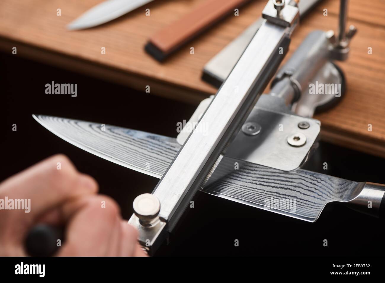Primo piano sulla mano dell'uomo utilizzando una macchina manuale per affilare Un coltello giapponese Foto Stock