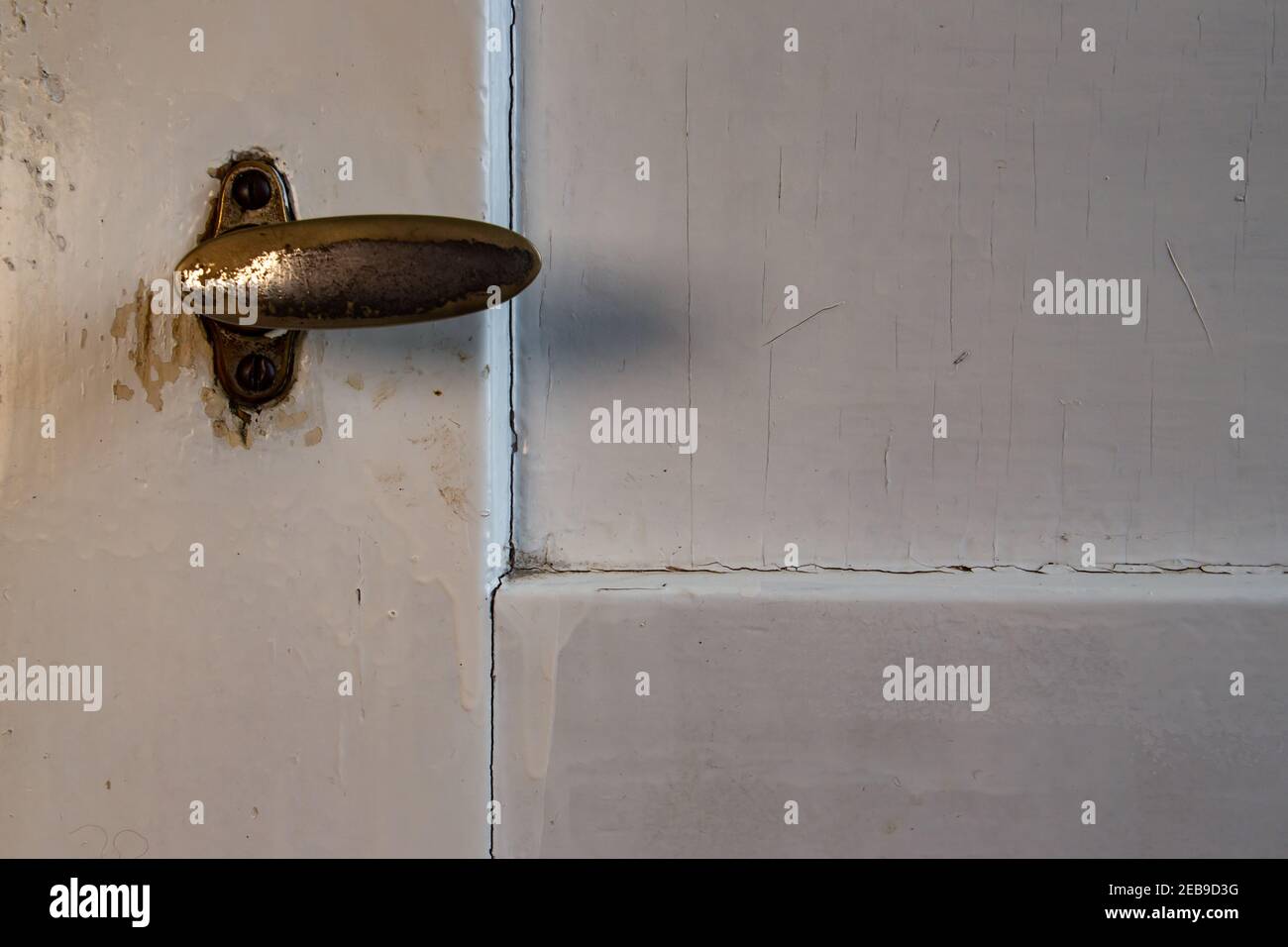 Vecchia maniglia della porta grugnosa su una porta verniciata di bianco Foto Stock