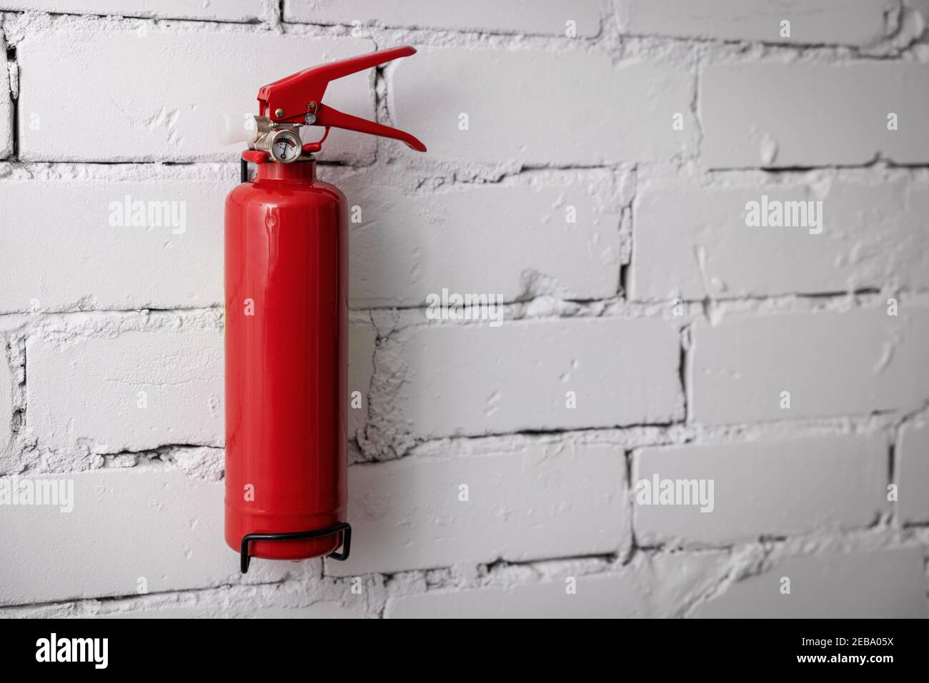 estintore rosso vuoto appeso a parete bianca in mattoni. spazio per la copia Foto Stock