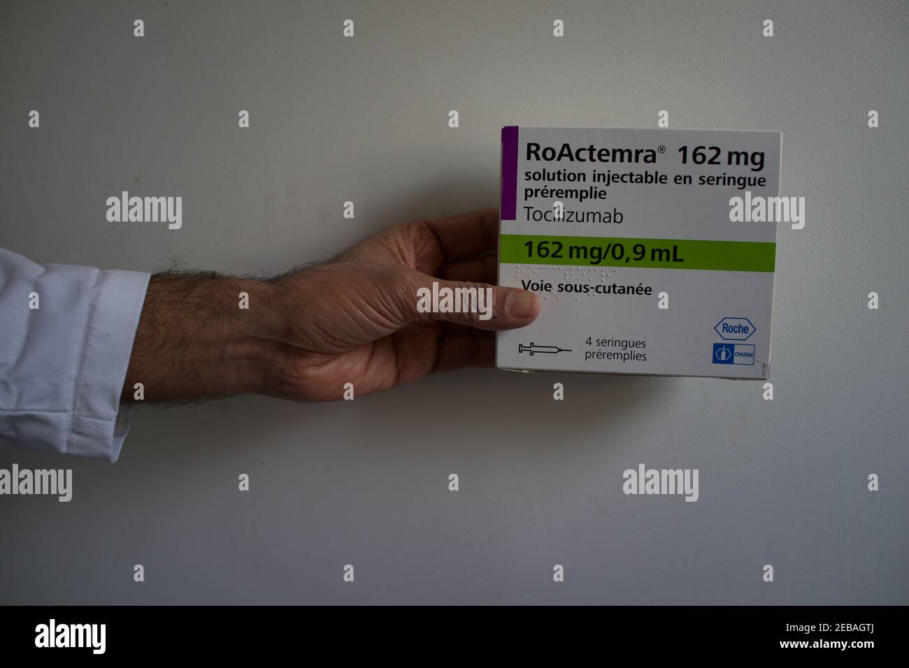 Mano che tiene Tocilizumab, Roactemra farmaco scatola, artrite farmaco utilizzato nel trattamento di Covid-19 Foto Stock