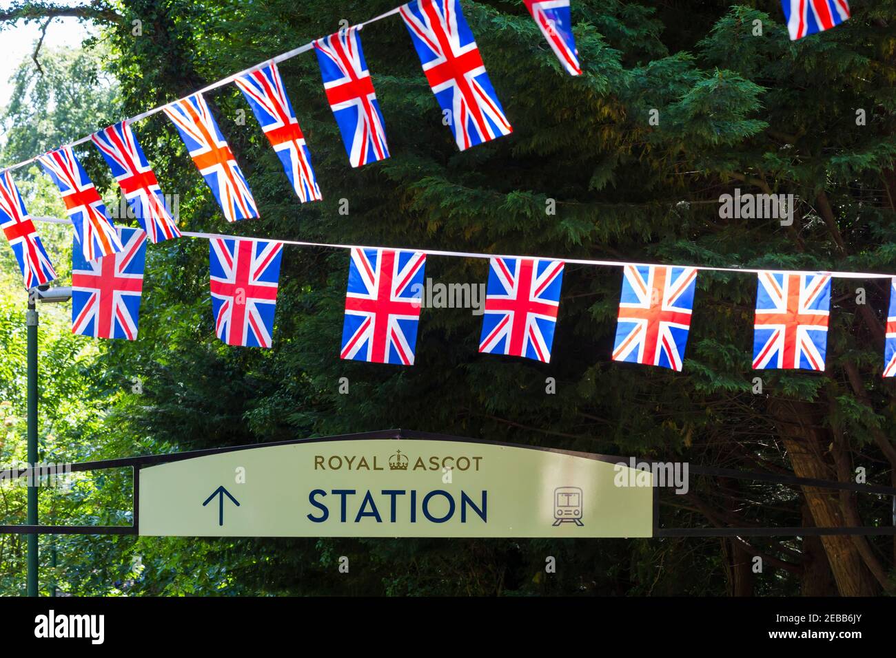Segno per la stazione di Royal Ascot, stazione ferroviaria, con Union Jack bunting a Ascot, Berkshire, Regno Unito nel mese di giugno Foto Stock