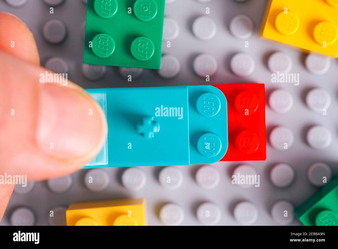 Tambov, Federazione Russa - 17 gennaio 2021 persona mano con Lego teal Brick Separator rimozione mattone rosso dalla piastra di base grigia Foto Stock