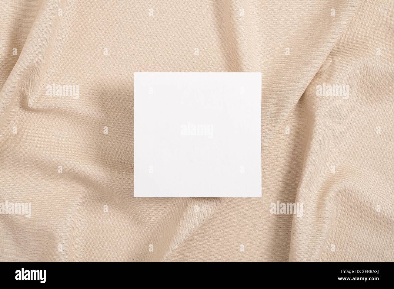 Carta bianca quadrata invito mockup su sfondo tessile beige Foto Stock