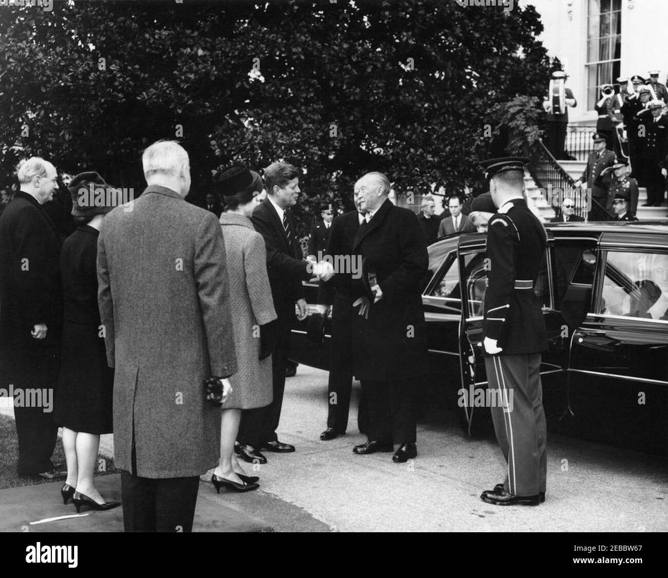 Cerimonie di arrivo per Konrad Adenauer, Cancelliere della Germania Occidentale, 10:45. Il presidente John F. Kennedy stringe le mani con il Cancelliere della Germania occidentale, il Dr. Konrad Adenauer, all'arrivo del Cancelliere Adenaueru2019 alla Casa Bianca. La First Lady Jacqueline Kennedy si trova accanto al presidente Kennedy; Libeth Werhahn, figlia del cancelliere Adenauer, esce dalla macchina sulla destra. Anche nella foto: Segretario di Stato degli Stati Uniti, Dean Rusk; Virginia Rusk; Vice Capo del protocollo, William J. Tonesk; Capo della polizia della Casa Bianca, maggiore Ralph C. u201cSmokeyu201d Stover; responsabile della sicurezza per il Dipartimento di Stato degli Stati Uniti, James M. Foto Stock