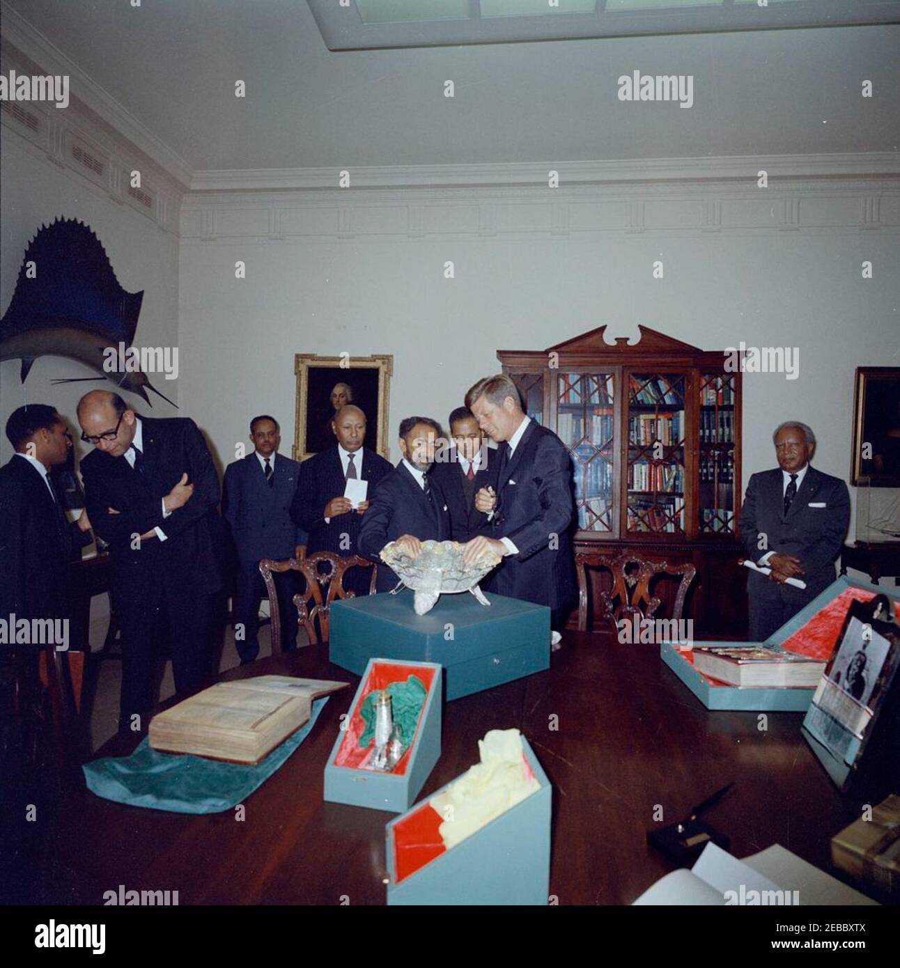 Incontro con Haile Selassie i, Imperatore d'Etiopia, ore 16:00. Il presidente John F. Kennedy guarda una ciotola filigrana durante uno scambio di doni con l'imperatore d'Etiopia, Haile Selassie i, nella stanza dei pesci della Casa Bianca. Da sinistra a destra: Non identificato; Ambasciatore degli Stati Uniti in Etiopia, Edward M. Korry; non identificato (nel retro); Ministro della Corte Imperiale di Etiopia, Tafarra-Worq Kidane-Wold; Imperatore Selassie; non identificato; Presidente Kennedy; Imru Haile Selassie, secondo cugino dell'Imperatore Selassie. Washington, D.C. Foto Stock