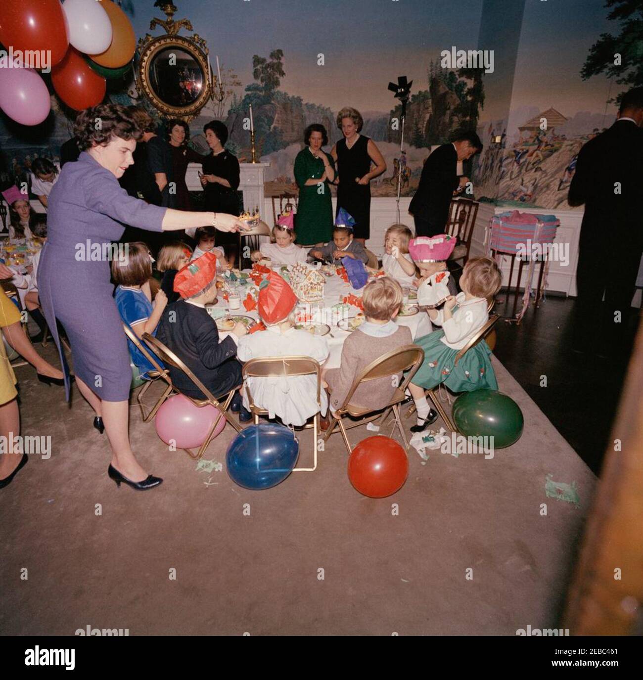 Festa di compleanno per Caroline Kennedy e John F. Kennedy, Jr. Caroline Kennedy (destra) mangia ad un tavolo nella Sala da pranzo del Presidente 2019s (residenza) della Casa Bianca, Washington, D.C., durante una festa di compleanno congiunta per lei e suo fratello, John F. Kennedy, Jr. Avery Hatcher, figlio del Segretario della Stampa associato, Andrew T. Hatcher, siede a sinistra di Caroline; Maria Shriver (a sinistra, di fronte) si trova di fronte a Caroline. Anche nella foto: Eunice Kennedy Shriver; Janet Auchincloss; primo segretario sociale Ladyu0027s, Letitia Baldrige; fotografo della Casa Bianca, Captain Cecil Stoughton. Foto Stock