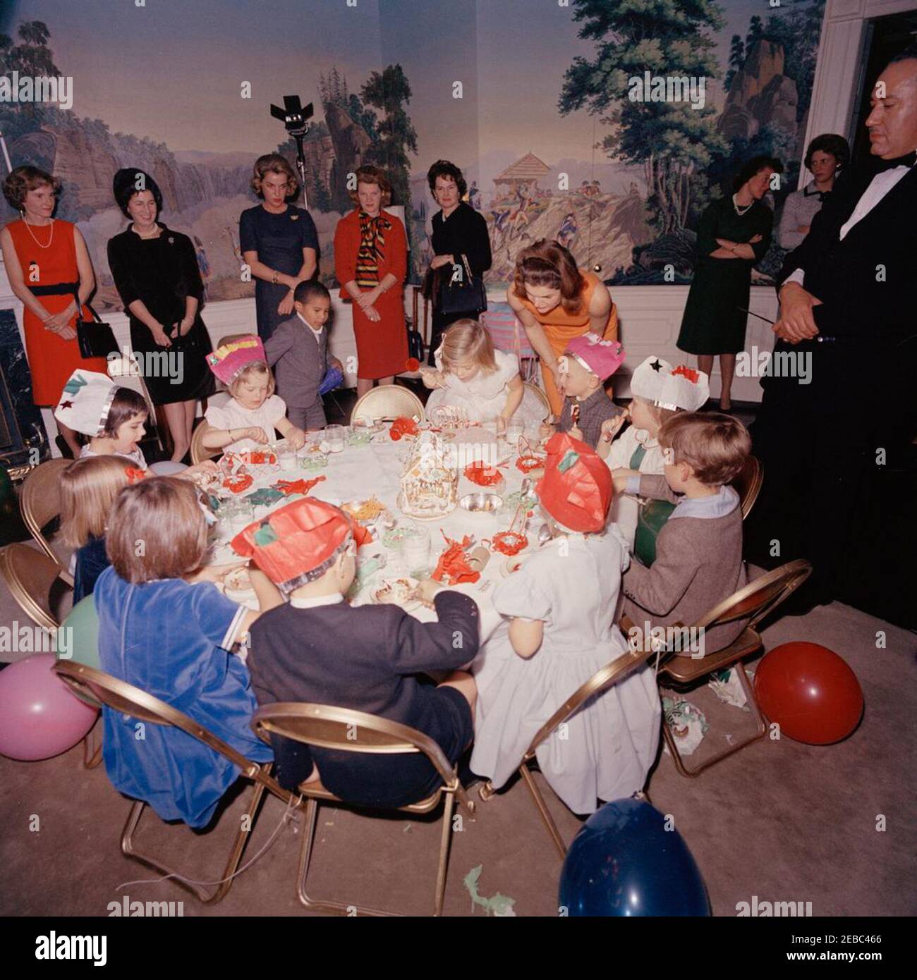 Festa di compleanno per Caroline Kennedy e John F. Kennedy, Jr. Caroline Kennedy soffia le candele sulla sua torta durante una festa di compleanno congiunta per lei e suo fratello, John F. Kennedy, Jr.; First Lady Jacqueline Kennedy si erge dietro la figlia. Avery Hatcher, figlio del segretario alla stampa associato Andrew T. Hatcher, si trova a sinistra di Caroline; Maria Shriver (con il retro alla telecamera) si trova a sinistra in primo piano. Anche nella foto: Janet Auchincloss; maggiordomo della Casa Bianca, John W. Ficklin. Presidentu2019s Dining Room (Residence), Casa Bianca, Washington, D.C. Foto Stock