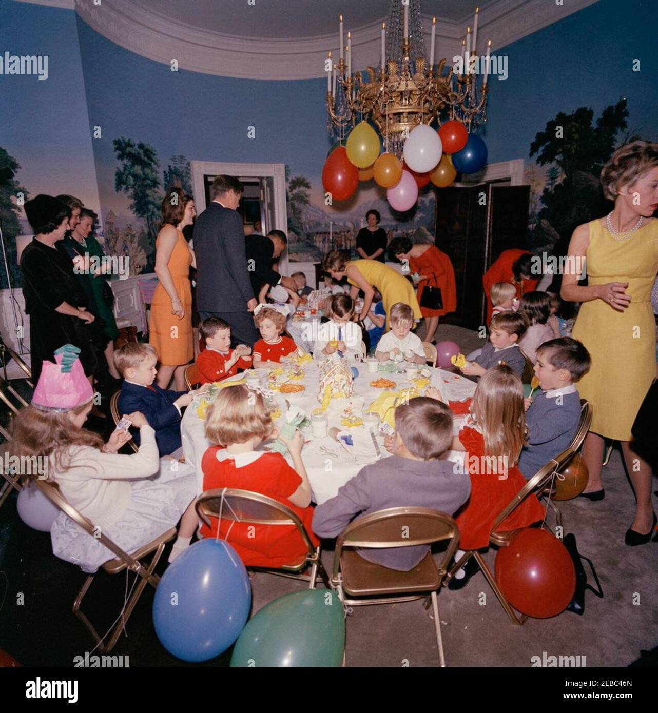 Festa di compleanno per Caroline Kennedy e John F. Kennedy, Jr. Il presidente John F. Kennedy e la First Lady Jacqueline Kennedy (entrambi al centro a sinistra) partecipano a una festa di compleanno congiunta per i loro bambini, Caroline Kennedy e John F. Kennedy, Jr.; Janet Auchincloss si trova all'estrema sinistra. Presidentu2019s Dining Room (Residence), Casa Bianca, Washington, D.C. Foto Stock