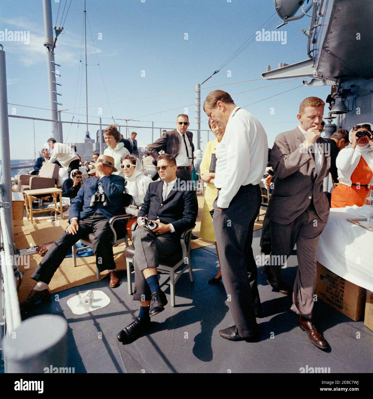 Il presidente Kennedy si accuda alla prima gara di Coppa Americau0027s. Il presidente John F. Kennedy e la First Lady Jacqueline Kennedy partecipano alla prima gara della Americau0027s Cup 1962 a bordo della USS Joseph P. Kennedy, Jr., al largo della costa di Newport, Rhode Island. Il presidente Kennedy (sullo sfondo a sinistra, con occhiali da sole) parla con il rappresentante John E. Fogarty (Rhode Island); la signora Kennedy (a sinistra) visita con il capo del protocollo, Angier Biddle Duke (per lo più nascosto). Anche nella foto: Hugh D. Auchincloss; Janet Auchincloss; Nancy Joy Salinger (moglie del Segretario della stampa, Pierre Salinger); Janet Jennings Auchincl Foto Stock