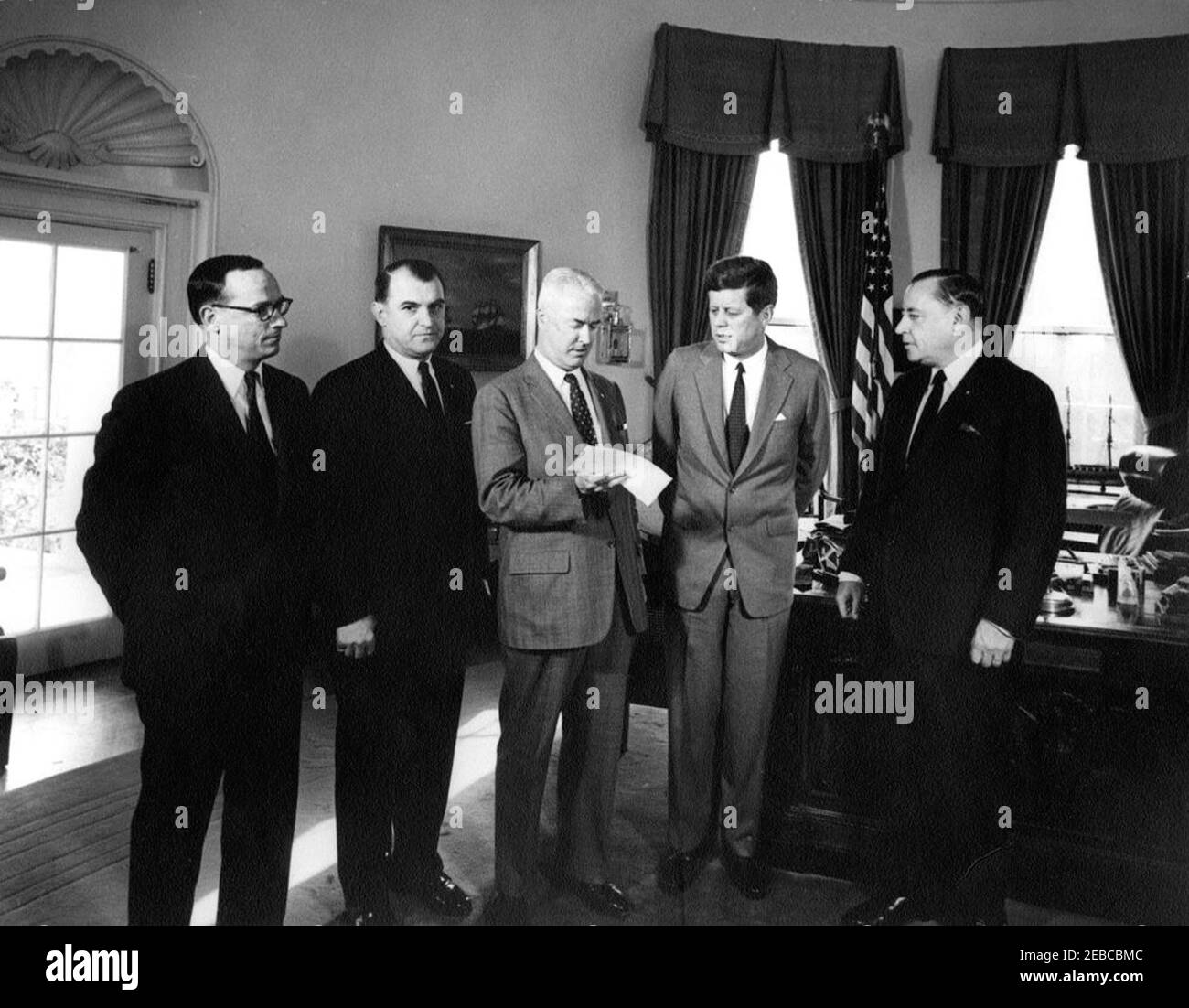 Presentazione di una donazione al 1962 United Givers Fund (UGF), ore 12. Il presidente John F. Kennedy presenta un assegno per un importo di 220,000 dollari dai fondi del Comitato inaugurale del 1961 ai rappresentanti del United Givers Fund della National Capital Area (UGF). Da sinistra a destra: Consigliere generale del Comitato Inaugurale del 1961, Fred M. Vinson, Jr.; Presidente dell'UGF, William Calomiris; Presidente dell'UGF, Mark Sullivan, Jr. (Assegno in carica); Presidente Kennedy; Presidente del Comitato Inaugurale del 1961, Edward H. Foley. Ufficio ovale, Casa Bianca, Washington, D.C. Foto Stock
