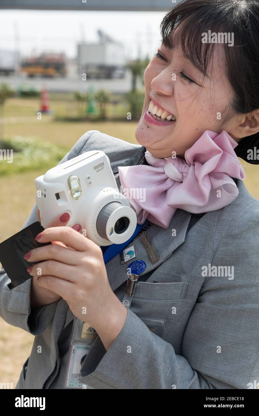 Hostess dell'aria con macchina fotografica istantanea all'aeroporto di Ube, Giappone Foto Stock