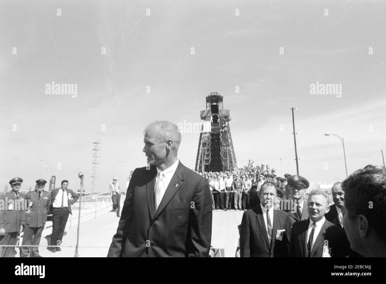 Presentazione della NASA (National Aeronautics and Space Administration) Distinguished Service Medal (DSM) all'astronauta John Herschel Glenn, Jr., a Cape Canaveral. L'astronauta tenente colonnello John H. Glenn, Jr. (Al centro, di fronte) e il presidente John F. Kennedy (per lo più nascosto, sul bordo inferiore destro dell'immagine) visitano il complesso di lancio 14, prima della cerimonia di presentazione della National Aeronautics and Space Administration (NASA), Medaglia di servizio al tenente colonnello Glenn; una folla di lavoratori assemblati guarda sopra. Il pad e la torre di servizio da cui Glenn è stato sollevato in orbita è visib Foto Stock