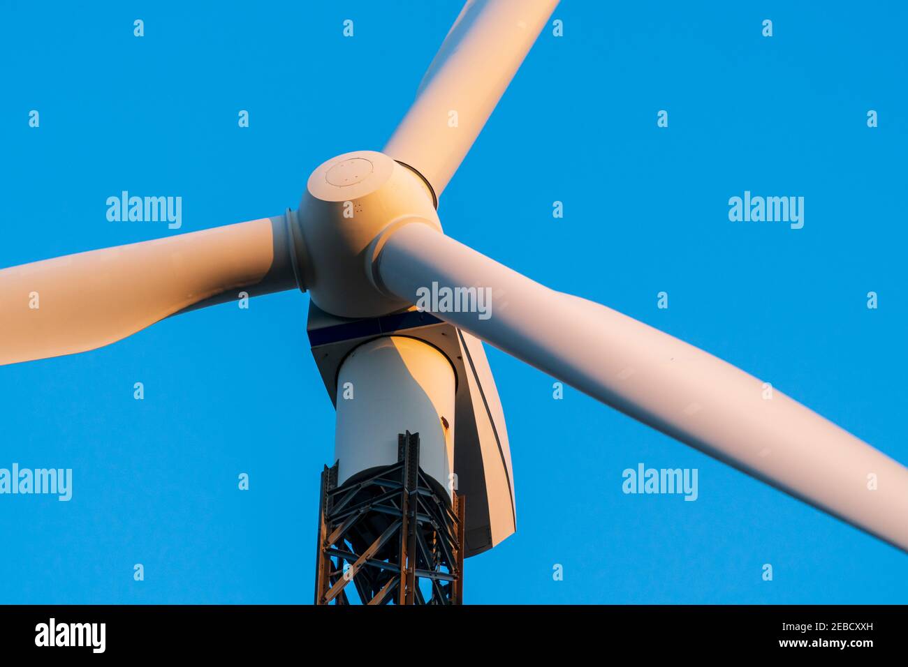 Turbine eoliche contro un cielo blu chiaro in una fattoria di turbine eoliche al tramonto. Vista ad angolo basso, primo piano su PROPELLER. Tema dell'energia rinnovabile, dell'energia pulita Foto Stock