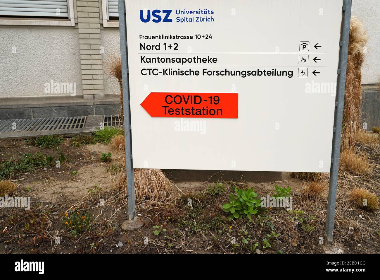 Cartello dell'Ospedale Universitario di Zurigo che mostra le indicazioni in tedesco e la freccia a forma di cartello per il coronavirus, covid-19 centro di test o stazione. Foto Stock