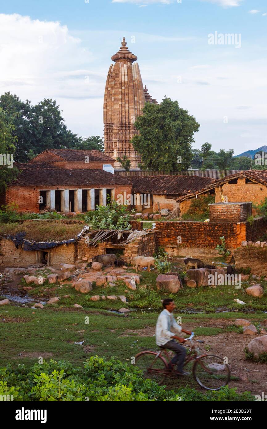 Khajuraho, Madhya Pradesh, India : UN uomo si muove in bicicletta davanti al Tempio di Vamana, parte del gruppo orientale del sito patrimonio dell'umanità dell'UNESCO Khajuraho Foto Stock