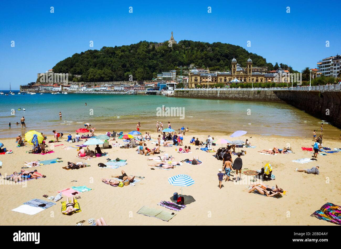 San Sebastian, Gipuzkoa, Paesi Baschi, Spagna - 12 luglio 2019 : la gente bagno al sole alla spiaggia di la Concha nella baia di la Concha. Urgull collina in backgroun Foto Stock