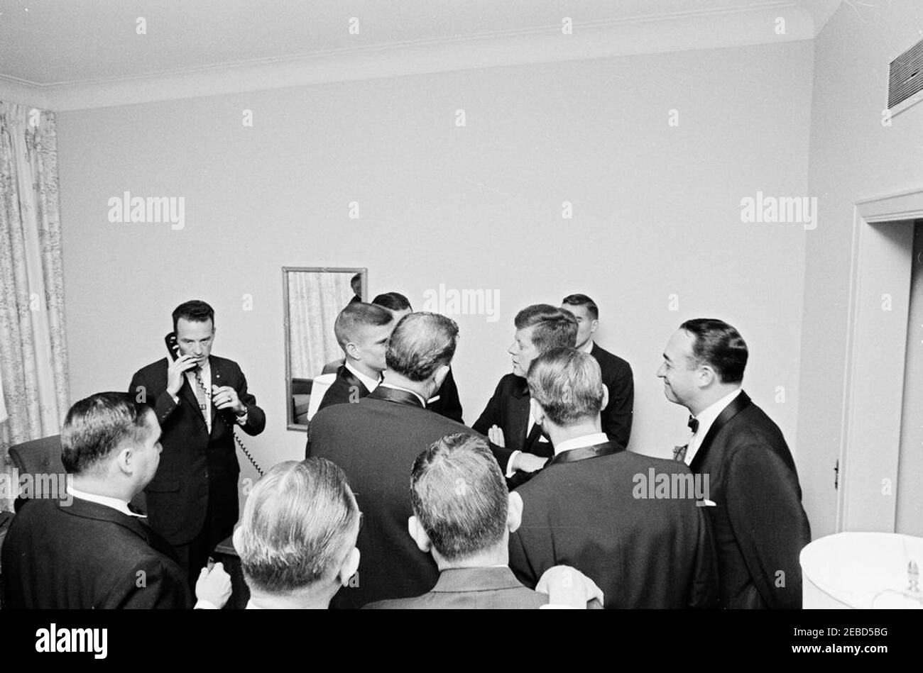 Football Hall of Fame Dinner, New York City, 10:00. Il presidente John F. Kennedy visita con i partecipanti alla cena della Football Hall of Fame. L-R: Segretario della stampa Pierre Salinger; membro dello staff della White House Army Signal Agency (WHASA), Jack Rubley; quarterback dell'Università dell'Alabama, Pat Trammel (parlando al presidente, faccia parzialmente nascosta); presidente Kennedy; membro dello staff della WHASA, John J. Cochran (dietro il presidente); sportscaster, Mel Allen. Camera 805, Waldorf Astoria Hotel, New York City. Foto Stock