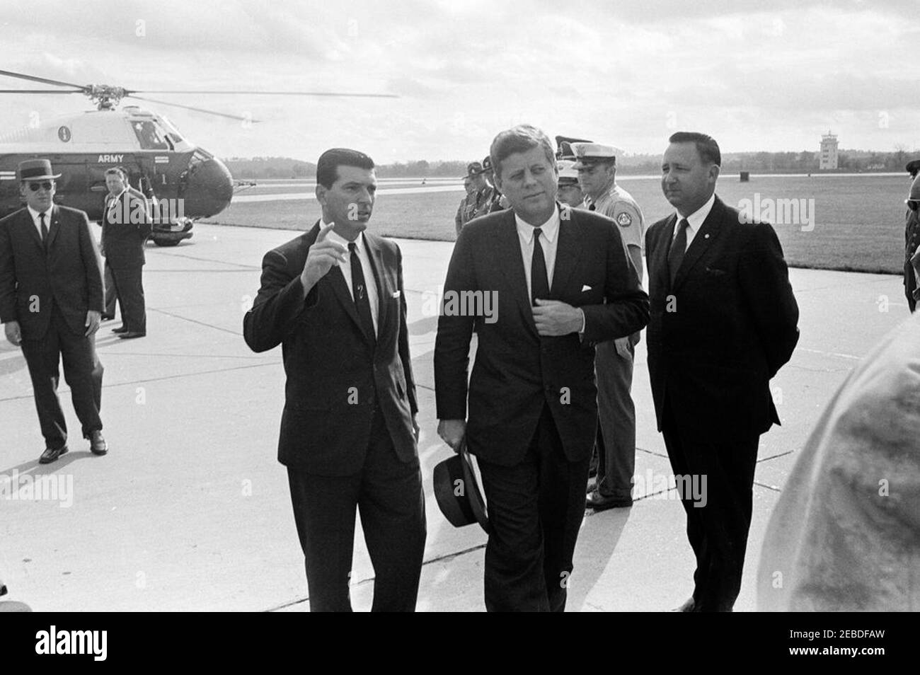 Viaggio in Oklahoma: Arrivo all'aeroporto di Fort Smith, Arkansas. Il presidente John F. Kennedy arriva all'aeroporto di Fort Smith a Fort Smith, Arkansas. Presidente Kennedy (al centro); agente del Servizio Segreto della Casa Bianca Roy Kellerman; altri non identificati. Elicottero dell'esercito degli Stati Uniti a sinistra. Foto Stock