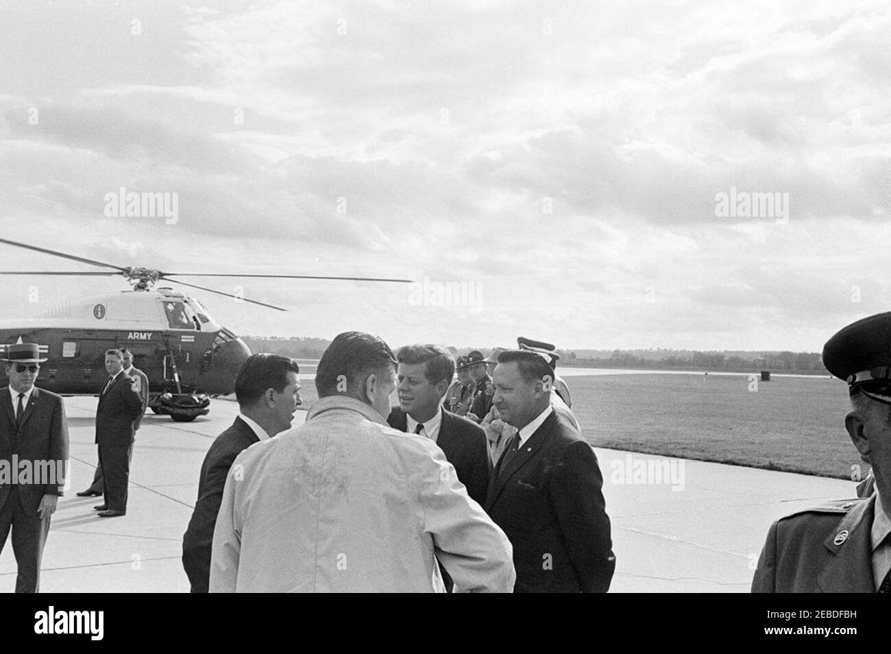 Viaggio in Oklahoma: Arrivo all'aeroporto di Fort Smith, Arkansas. Il presidente John F. Kennedy arriva all'aeroporto di Fort Smith a Fort Smith, Arkansas. Agente di servizio segreto Gerald u201cJerryu201d Behn (centro, ritorno alla telecamera); Presidente Kennedy (centro); altri non identificati. Elicottero dell'esercito degli Stati Uniti a sinistra. Foto Stock