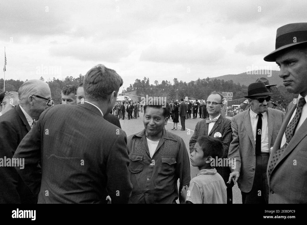 Viaggio in Oklahoma: Cerimonia di taglio del nastro a Ouachita National Park Road, Big Cedar, Oklahoma. Il presidente John F. Kennedy partecipa alla cerimonia di taglio del nastro a Ouachita National Forest Road. Il senatore dell'Oklahoma Robert Kerr (all'estrema sinistra); l'agente di servizio segreto Gerald u201cJerryu201d Behn (dietro e a destra del senatore Kerr, parzialmente nascosto); il presidente Kennedy (al centro, di nuovo alla macchina fotografica); altri non identificati. Big Cedar, Oklahoma. Foto Stock