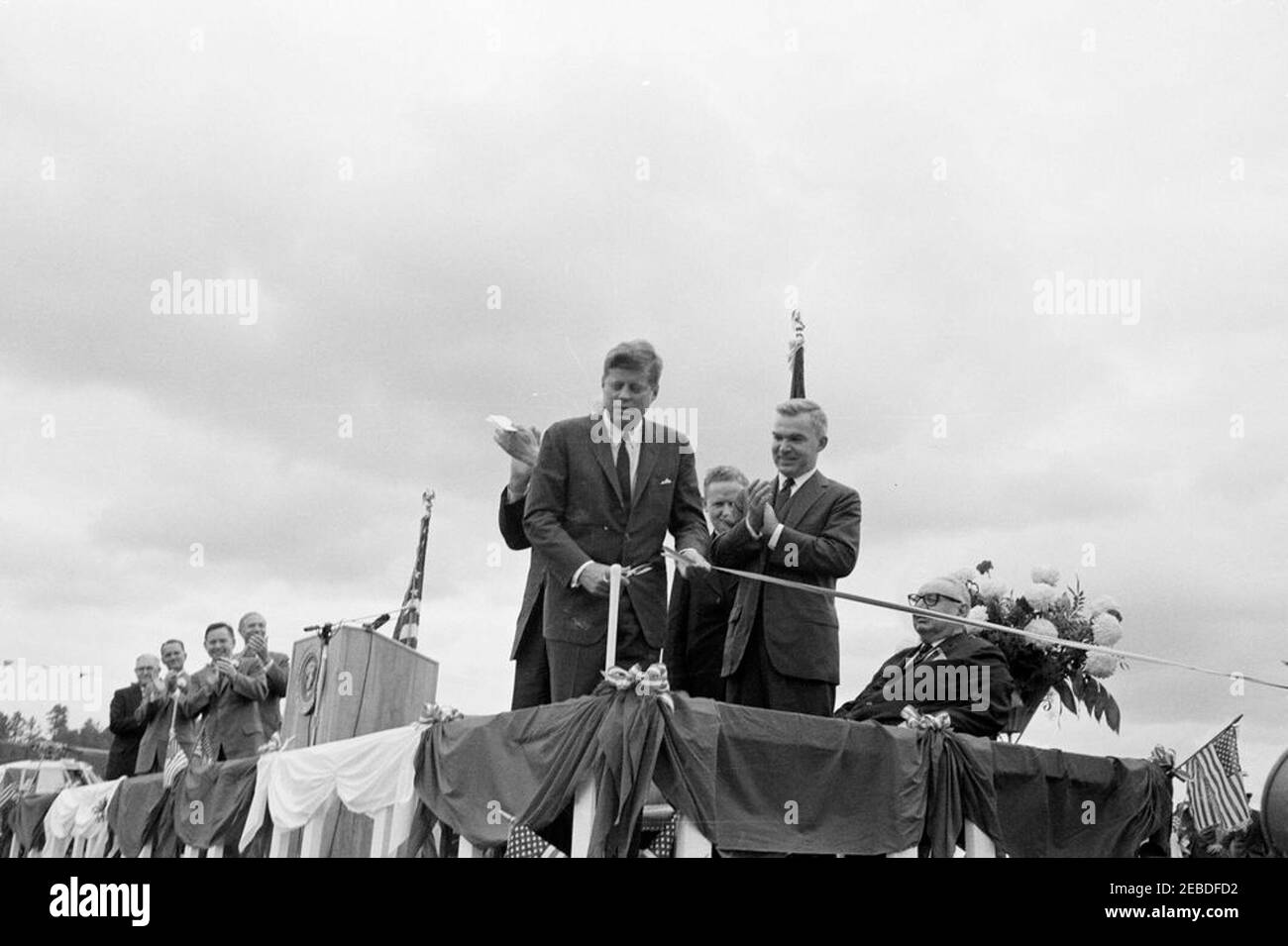 Viaggio in Oklahoma: Cerimonia di taglio del nastro a Ouachita National Park Road, Big Cedar, Oklahoma. Il presidente John F. Kennedy partecipa alla cerimonia di taglio del nastro a Ouachita National Forest Road. Presidente Kennedy (al centro); altri non identificati. Big Cedar, Oklahoma. Foto Stock