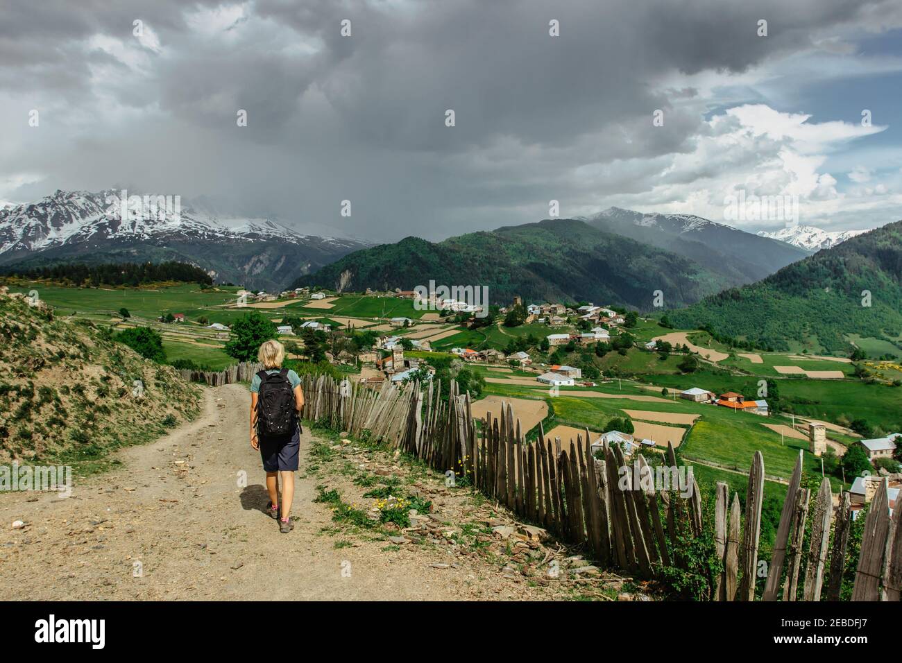 Girl trekking nel Grande Caucaso, Georgia.Snowy picchi di montagne, prati verdi, villaggio rurale. Vista sulla valle e sulle montagne rocciose. HPP attivo Foto Stock