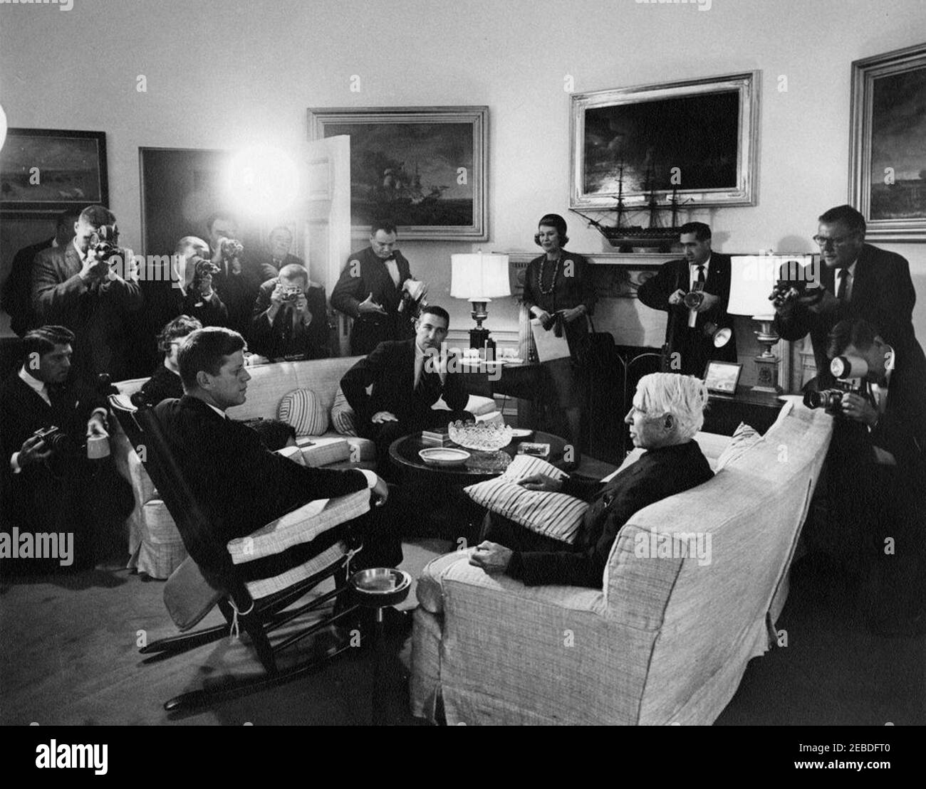 Visita di Carl Sandburg, 12:40. Il presidente John F. Kennedy (in sedia a dondolo) visita con l'autore e poeta Carl Sandburg (a destra); il segretario dell'interno, Stewart Udall, siede al centro. Anche nella foto: Fotografo della Casa Bianca, Captain Cecil Stoughton; elettricista della rete dei media della Casa Bianca, Cleve Ryan; fotografo della Casa Bianca, capo Robert L. Knudsen; fotografo della stampa per United Press Movietone, Thomas J. Craven, Sr. Oval Office, Casa Bianca, Washington, D.C. Foto Stock