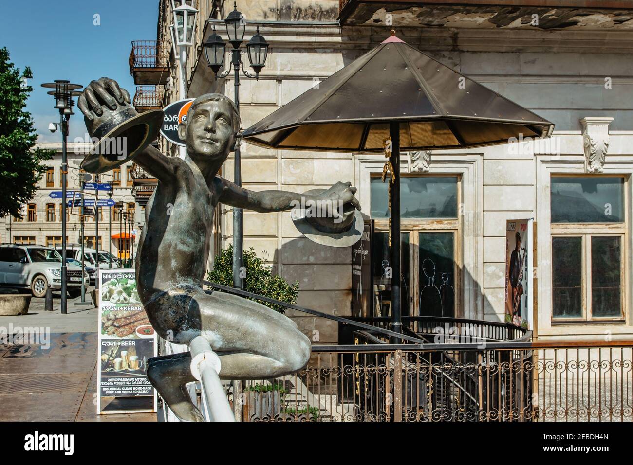Kutaisi, Georgia - 8 giugno 2019. Statua di bronzo del ragazzo con cappelli in mano sul Ponte Bianco, Tetrikhidi, attraverso il fiume Rioni. Scultura di ragazzo felice Foto Stock