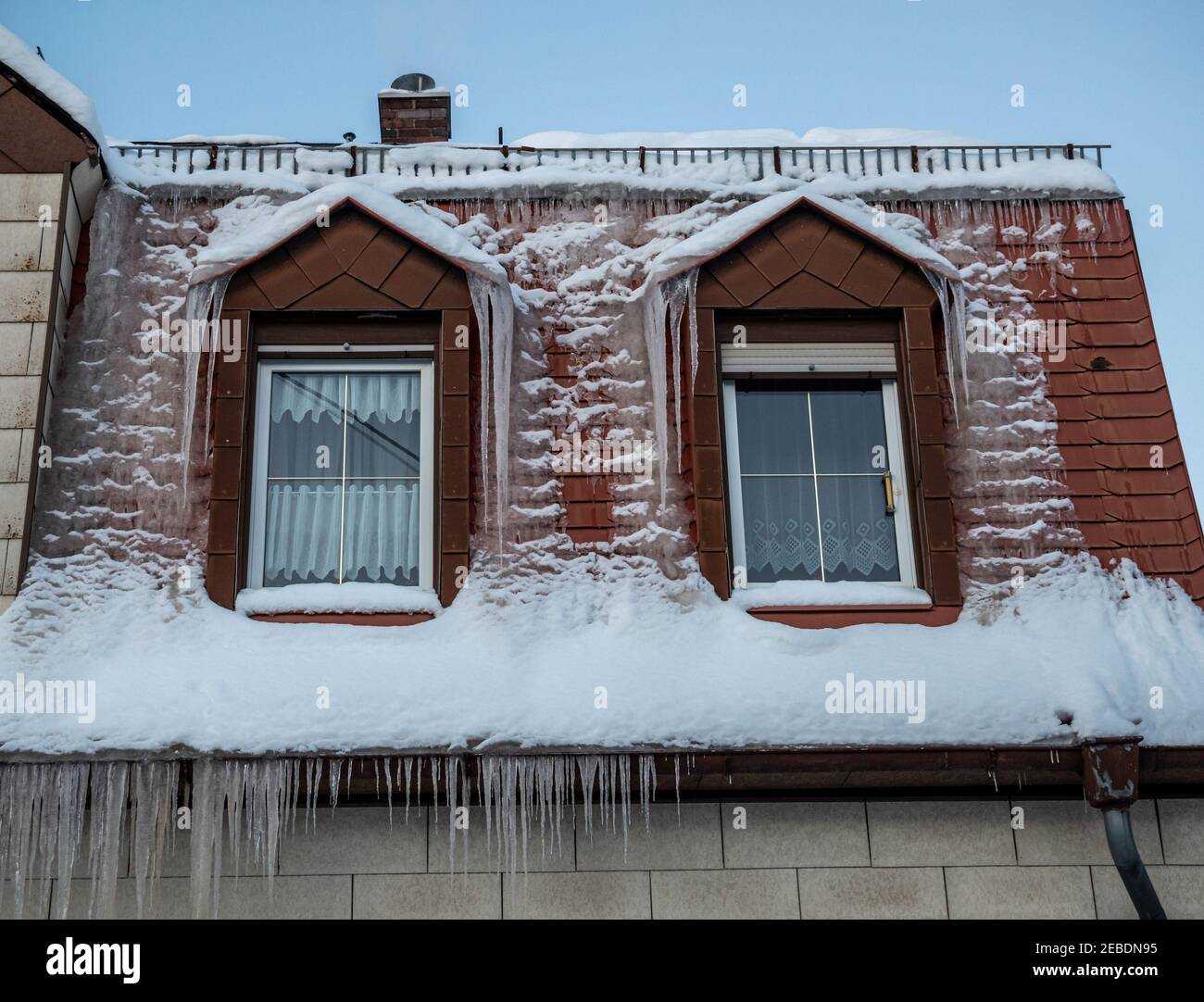 Tetto di una casa completamente congelato con icicles Foto Stock