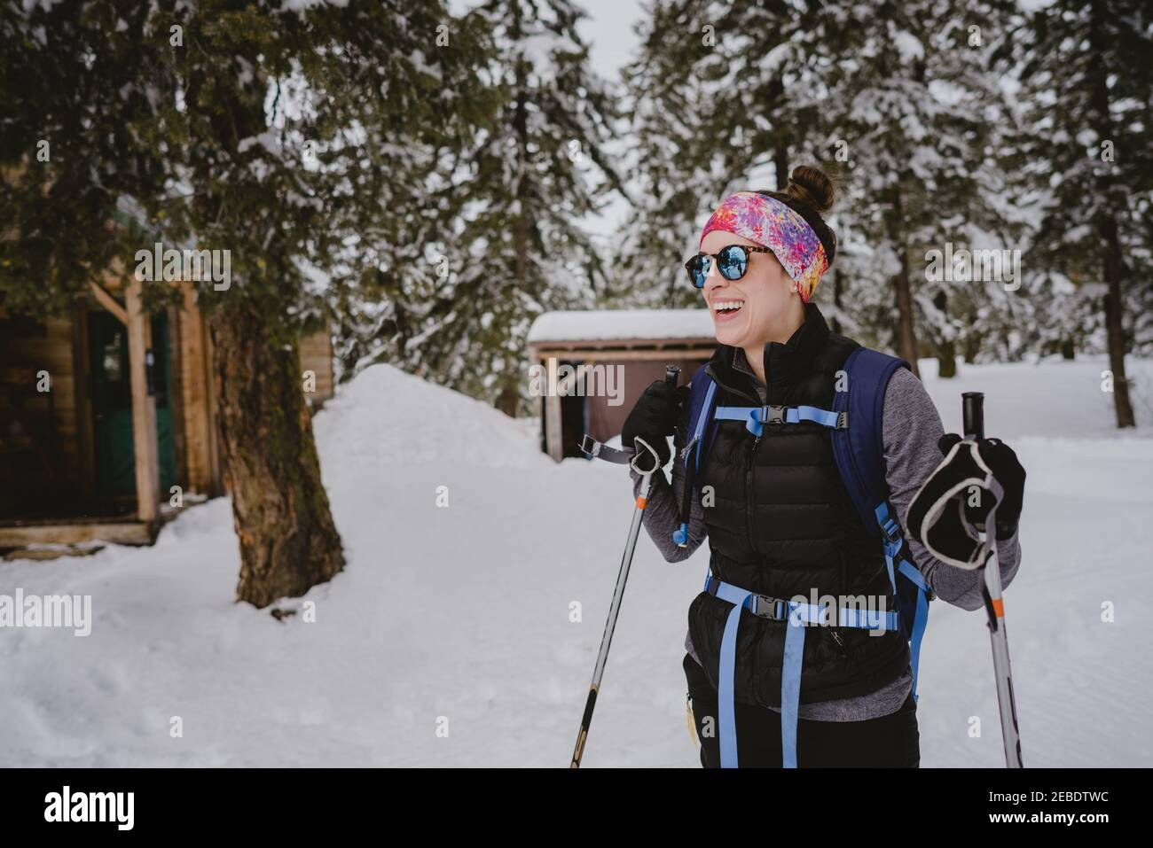 Una donna con occhiali da sole e risate puffy mentre XC sci in cabina Foto Stock