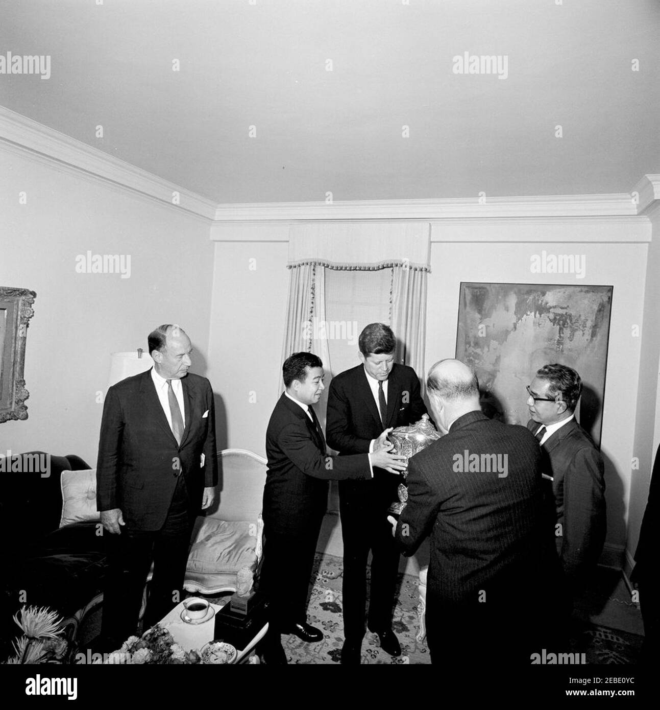Viaggio a New York: Incontro con il Principe Norodom Sihanouk di Cambogia, alle 16:00. Il principe Norodom Sihanouk della Cambogia presenta il presidente John F. Kennedy con un'urna d'argento nella suite Presidentu2019s al Carlyle Hotel, New York City, New York. (L-R) Ambasciatore degli Stati Uniti presso le Nazioni Unite Adlai Stevenson; Principe Sihanouk; Presidente Kennedy; John Steeves, Vice Segretario di Stato aggiunto per gli Affari dell'Estremo Oriente (di ritorno alla camera); Ministro degli Affari Esteri della Cambogia Nhiek Tioulong. Foto Stock