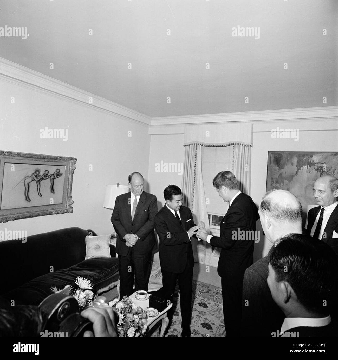 Viaggio a New York: Incontro con il Principe Norodom Sihanouk di Cambogia, alle 16:00. Il presidente John F. Kennedy detiene una piccola statua presentata dal principe Norodom Sihanouk della Cambogia nella Suite del Presidente 2019s al Carlyle Hotel, New York City, New York. (L-R) Ambasciatore degli Stati Uniti presso le Nazioni Unite Adlai Stevenson; Principe Sihanouk; Presidente Kennedy; John Steeves, Vice Segretario di Stato aggiunto per gli Affari dell'Estremo Oriente (ritorno alla camera); Ambasciatore della Cambogia Nong Kinny (ritorno alla camera, in basso a destra); Ambasciatore degli Stati Uniti in Cambogia William Trimble. Foto Stock