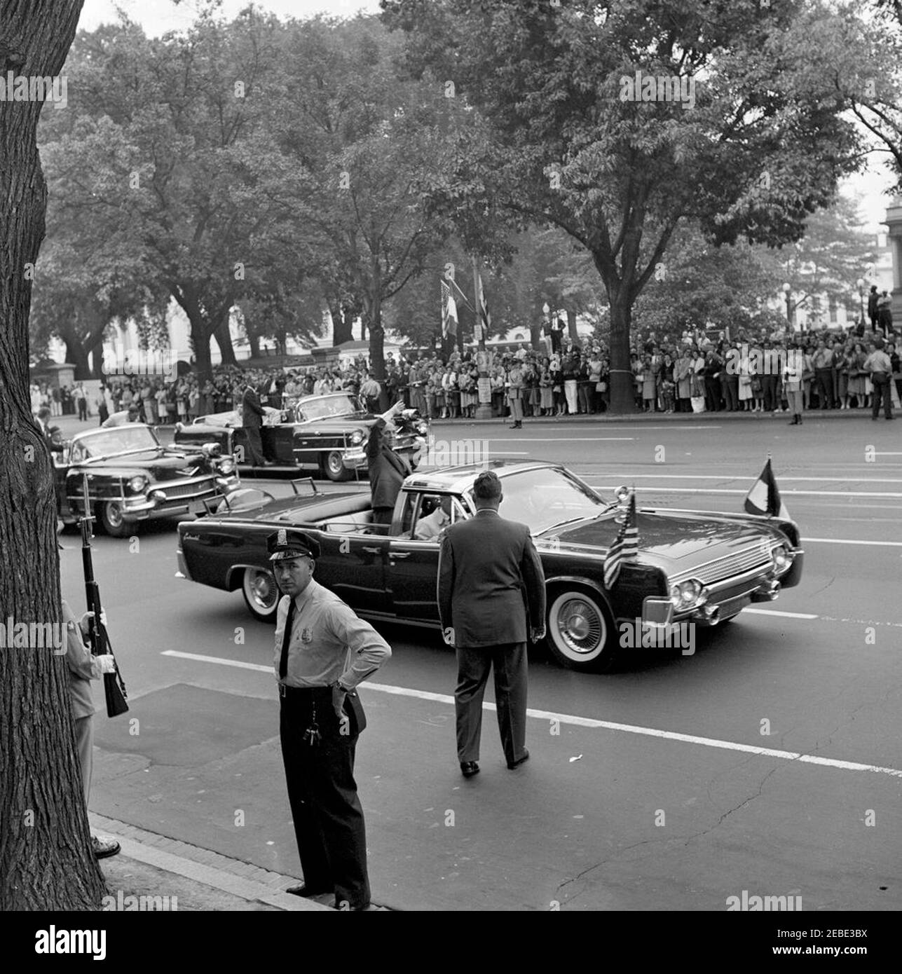 Arrivo cerimonie per il Dr. Manuel Prado Ugarteche, presidente del Perù 12:00 PM. Una grande folla guarda come il motociclista presidenziale arriva a Blair House, Washington, D.C. il presidente Dr. Manuel Prado Ugarteche del Perù si trova nella limousine presidenziale aperta (Lincoln-Mercury Continental convertibile) e le onde alla folla. Foto Stock