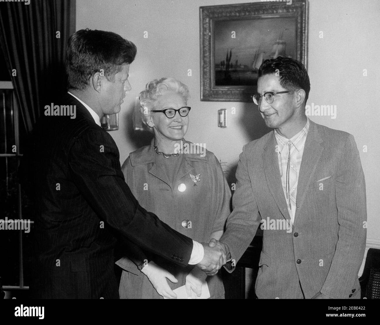 Annuncio del primo alloggio pubblico per gli Indiani, 11:42. Il presidente John F. Kennedy annuncia la prima sovvenzione di pianificazione di alloggi pubblici per una prenotazione indiana (dei nativi americani), Oval Office, White House, Washington, D.C. il presidente Kennedy si congratula con la tribù Oglala Sioux della riserva di Pine Ridge nel South Dakota e con l'autorità di Oglala Sioux Housing. (L-R) Presidente Kennedy; Commissario per l'edilizia pubblica Marie McGuire; capo Johnson Holy Rock dell'Oglala Sioux Tribe. Foto Stock