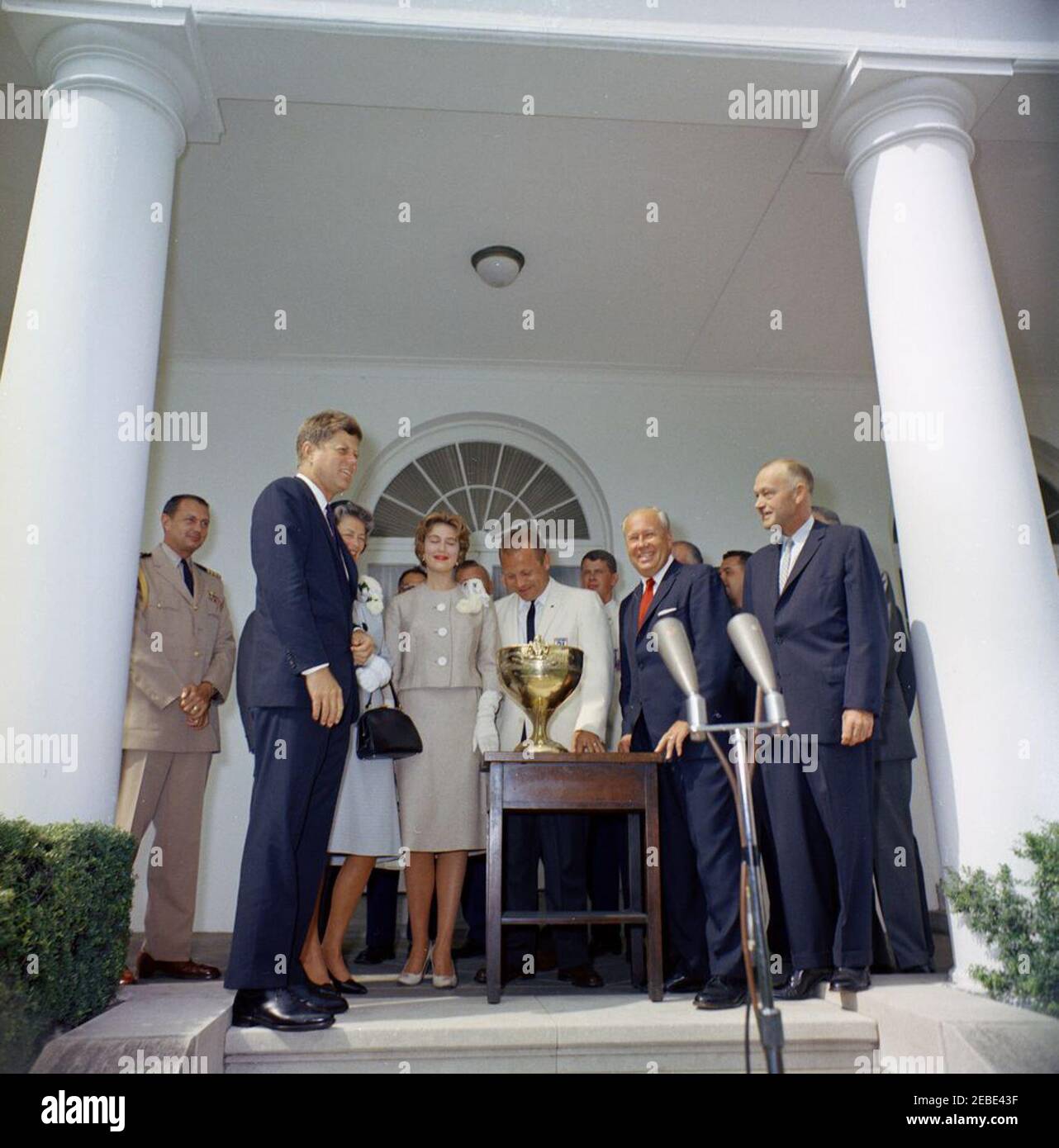 Presentazione del Trofeo Regatta della Coppa Presidentu0027s 1961, ore 12. Il presidente John F. Kennedy presenta la Coppa Presidentu0027s a Bill Muncey, vincitore della corsa illimitata degli idrovolanti della Coppa Presidentu0027s, nel Rose Garden, White House, Washington, D.C. (L-R) Naval Aide al presidente Tazewell Shepard, Jr.; il presidente Kennedy; due donne non identificate; Bill Muncey; membro dell'equipaggio Jerry Rhodes; Proprietario della barca vincitrice Willard Rhodes; non identificato (per lo più nascosto); Rappresentante Don Magnuson di Washington. Foto Stock