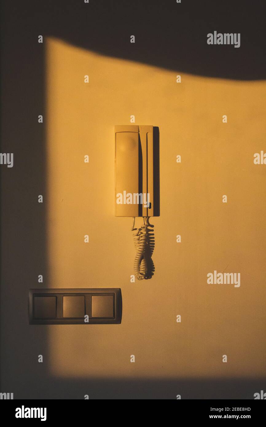 telefono della casa su parete bianca con luce solare giallastra Foto Stock