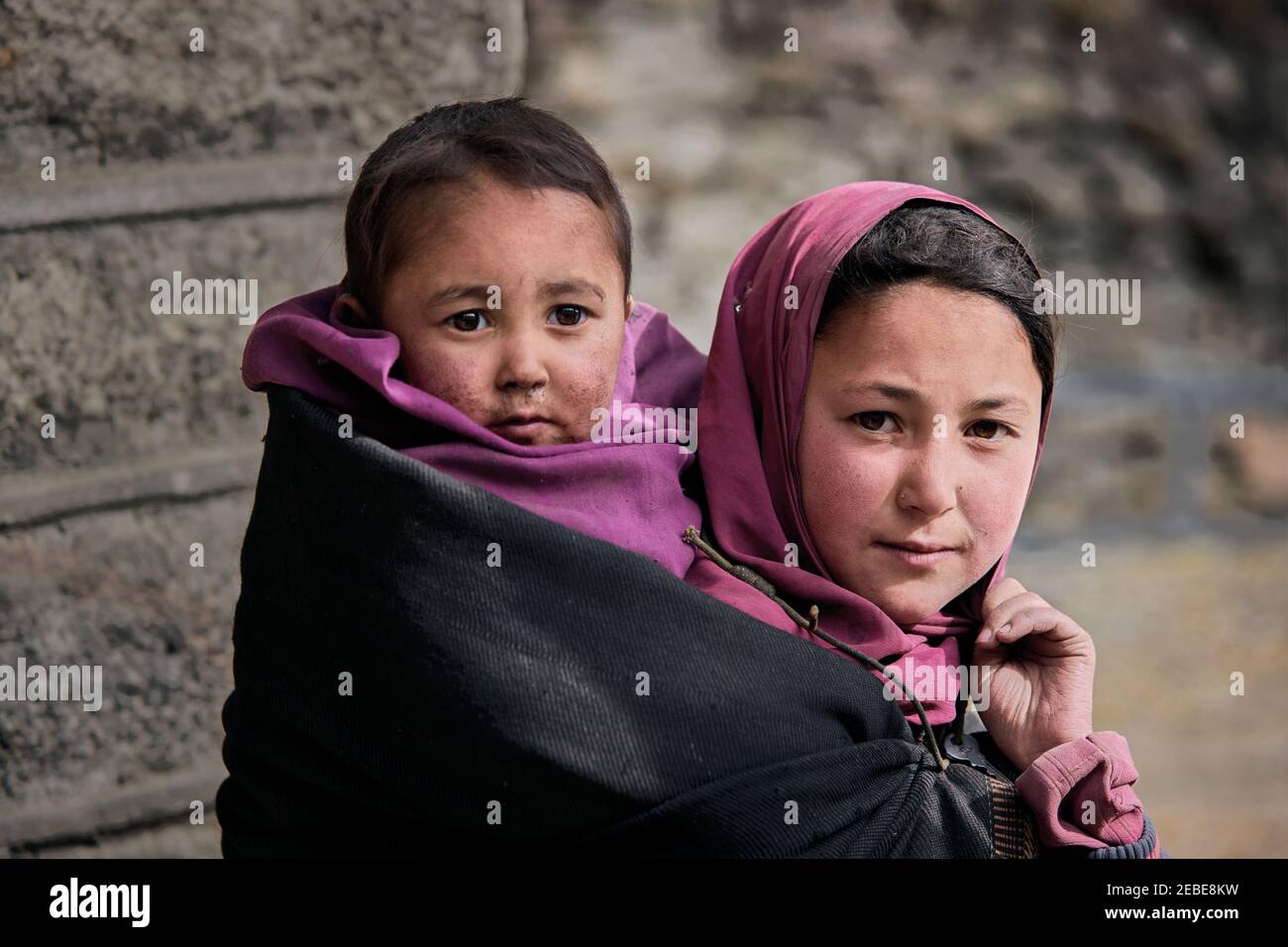 Ragazza che porta il suo fratello sulla parte posteriore in montagne del Pakistan Foto Stock