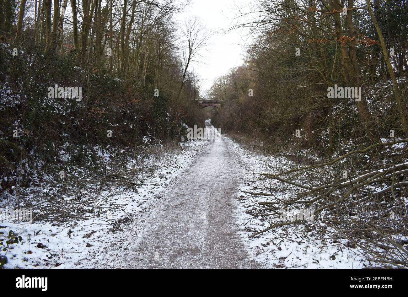 Vista che guarda giù la neve coperta Worth Way verso un ponte di strada di mattoni che attraversa il ponte vicino al villaggio di Crawley giù a West Sussex, Regno Unito. Foto Stock