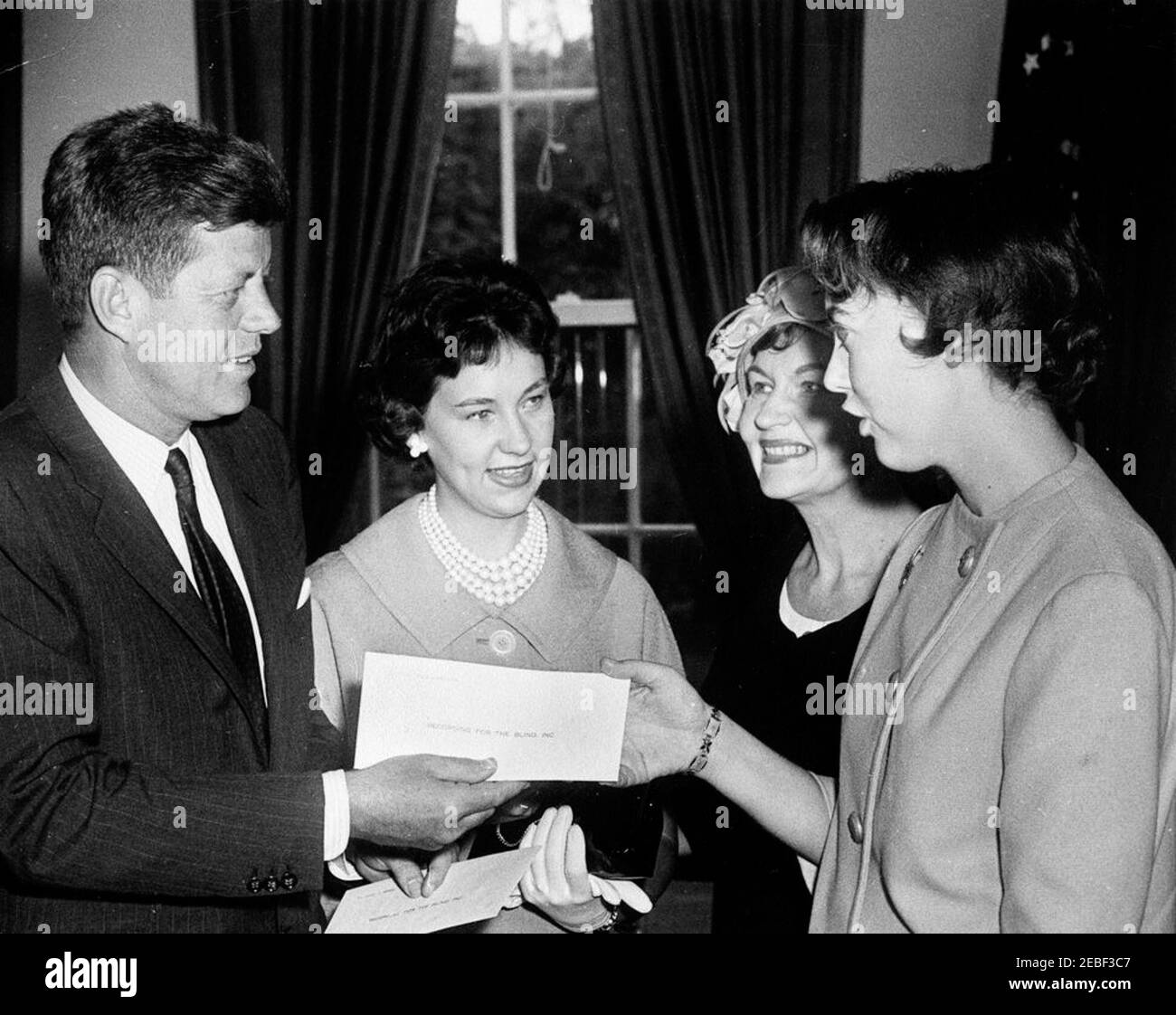 Presentazione dei Premi per il conseguimento degli obiettivi scolastici assegnati da Recording for the Blind, Inc. Dal Presidente Kennedy, ore 12:05. Per conto di Recording for the Blind, Inc., il presidente John F. Kennedy presenta un premio per il raggiungimento degli obiettivi scolastici a Helen Vivian Aareskjold. Il vincitore del premio Cheryl Lynn Martin e sua madre, la sig.ra James Martin, stanno accanto. Ufficio ovale, Casa Bianca, Washington, D.C. Foto Stock