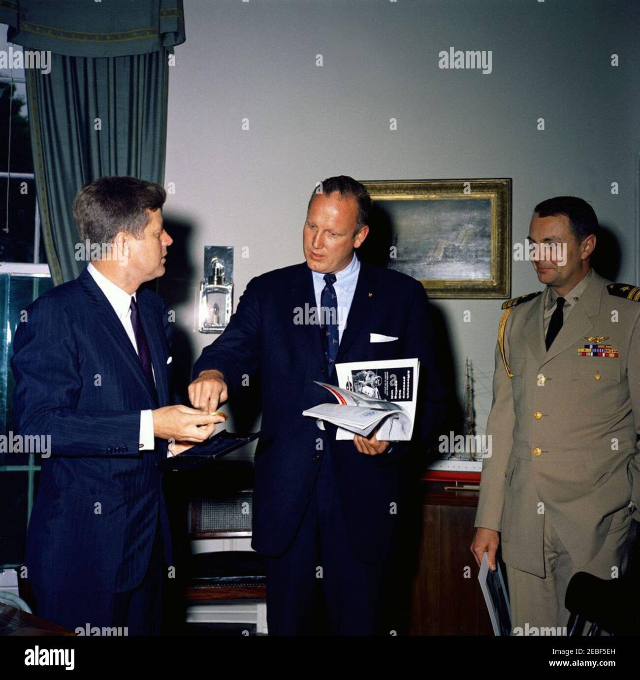 Presentazione di una medaglia d'oro per commemorare il 50° anniversario dell'aviazione navale al presidente Kennedy, alle 17:15. Presentazione al presidente John F. Kennedy di una medaglia d'oro per commemorare il 50° anniversario dell'aviazione navale. L-R: Il presidente Kennedy; il presidente della Lega della Marina, Frank G. Jameson; l'Aide navale al presidente, il comandante Tazewell Shepard. Ufficio ovale, Casa Bianca, Washington, D.C. Foto Stock