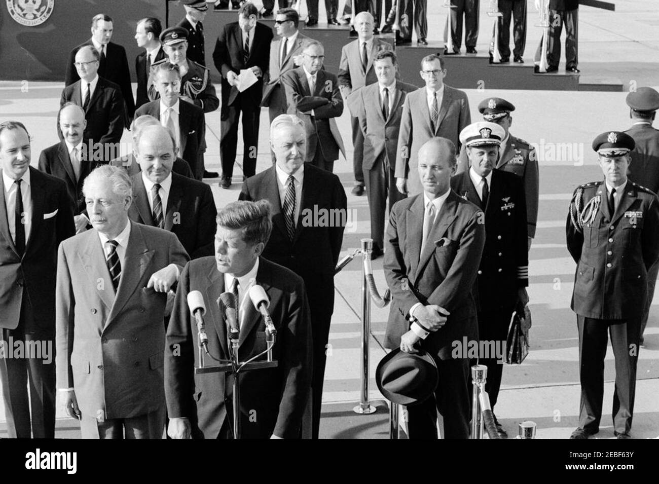 Cerimonie di arrivo per Harold Macmillan, primo ministro della Gran Bretagna, 16:50. Il presidente John F. Kennedy ha espresso le sue parole di benvenuto durante le cerimonie di arrivo in onore del primo ministro della Gran Bretagna, Harold Macmillan. Sulla piattaforma di revisione (L-R): Ambasciatore della Gran Bretagna, Sir David Ormsby-Gore (a ritroso); primo ministro Macmillan; Segretario di Stato, Dean Rusk; Presidente Kennedy (ai microfoni); Ambasciatore degli Stati Uniti in Gran Bretagna, David K. E. Bruce; e Capo del protocollo, Angier Biddle Duke. Anche nella foto: Vice Segretario di Stato aggiunto per gli Affari europei, W. Foto Stock