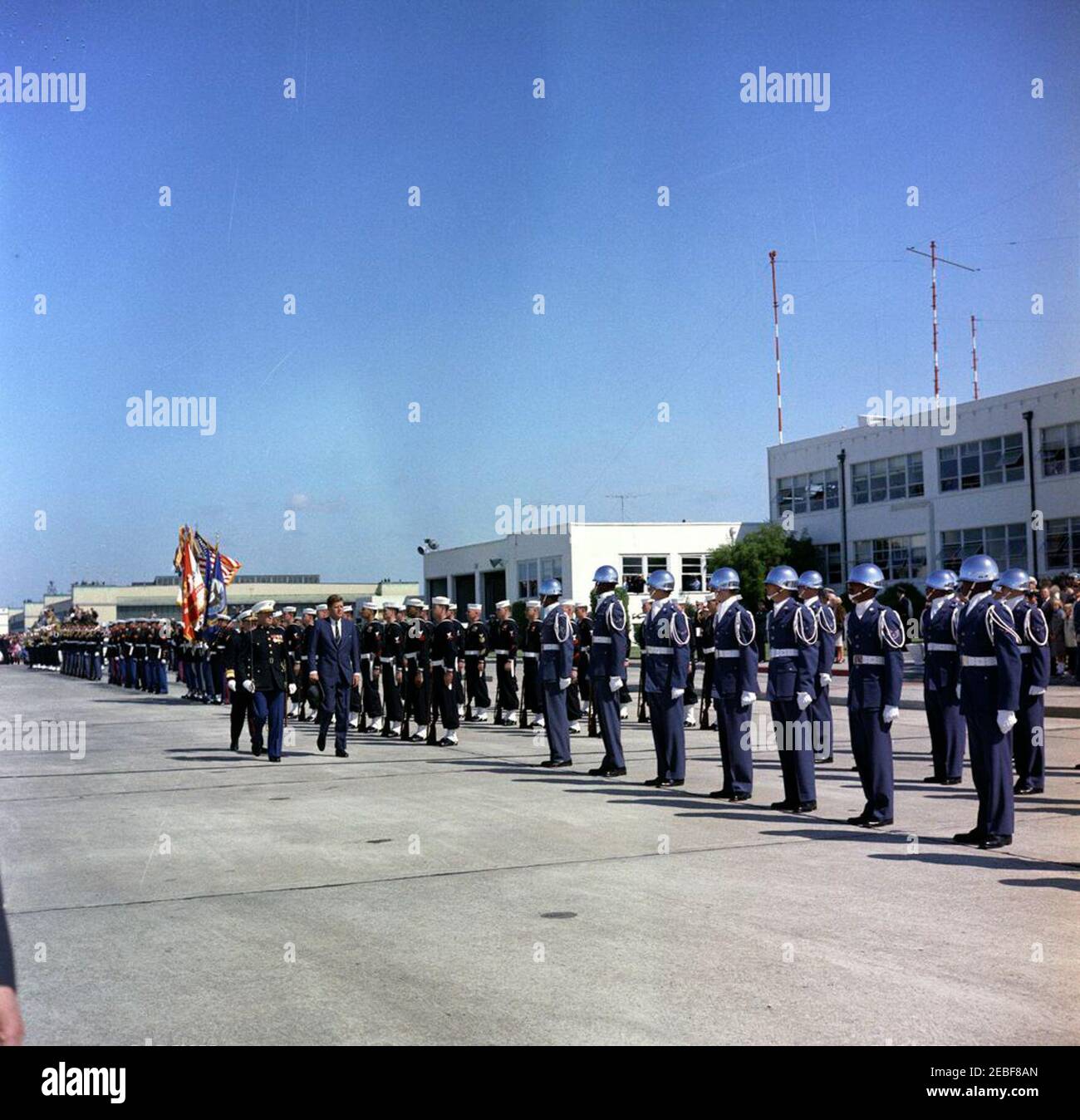 Viaggio in California: Alameda Naval Air Station, 11:00. Il presidente John F. Kennedy ispeziona le truppe al suo arrivo alla base aerea navale di Alameda in Alameda, California. Il vice ammiraglio Robert Goldthwaite (sul retro) e un ufficiale del corpo dei Marine non identificato accompagnano il presidente Kennedy sulla sinistra. Foto Stock