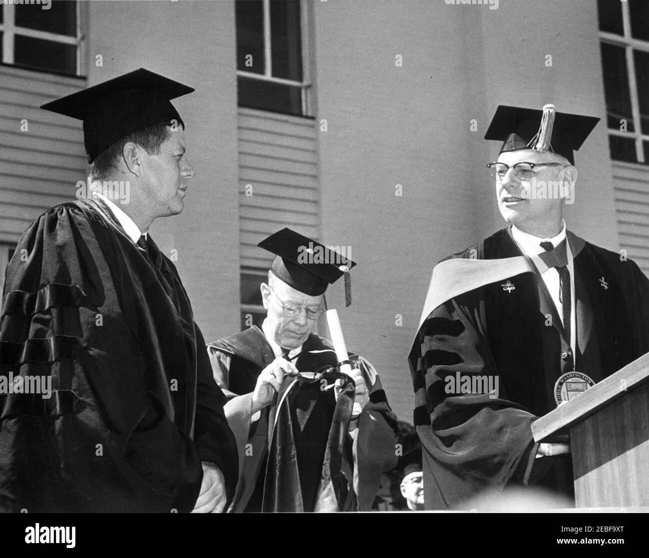 Indirizzo alla George Washington University, 10:45. Il presidente della George Washington University, il Dr. Thomas Henry Carroll (a destra), parla al leggio prima di presentare il presidente John F. Kennedy con il grado onorario di Dottore delle leggi, durante la cerimonia di inaugurazione del Dr. Carrollu2019 come presidente dell'università. John F. Latimer, Marshal e Dean della George Washington University, si trova alle spalle. George Washington University, Washington, D.C. Foto Stock