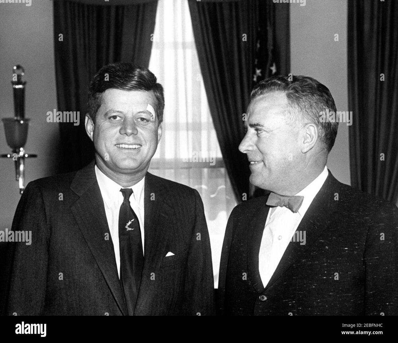 Incontro con l'Ambasciatore d'Irlanda Thomas J. Kiernan, presentazione di Shamrocks e Kennedy Coat of Arms, ore 10:00. Incontro con l'Ambasciatore d'Irlanda, Thomas J. Kiernan. Il presidente John F. Kennedy (con un bendaggio sopra l'occhio sinistro); il membro del Congresso John E. Fogarty (Rhode Island). Ufficio ovale, Casa Bianca, Washington, D.C. Foto Stock