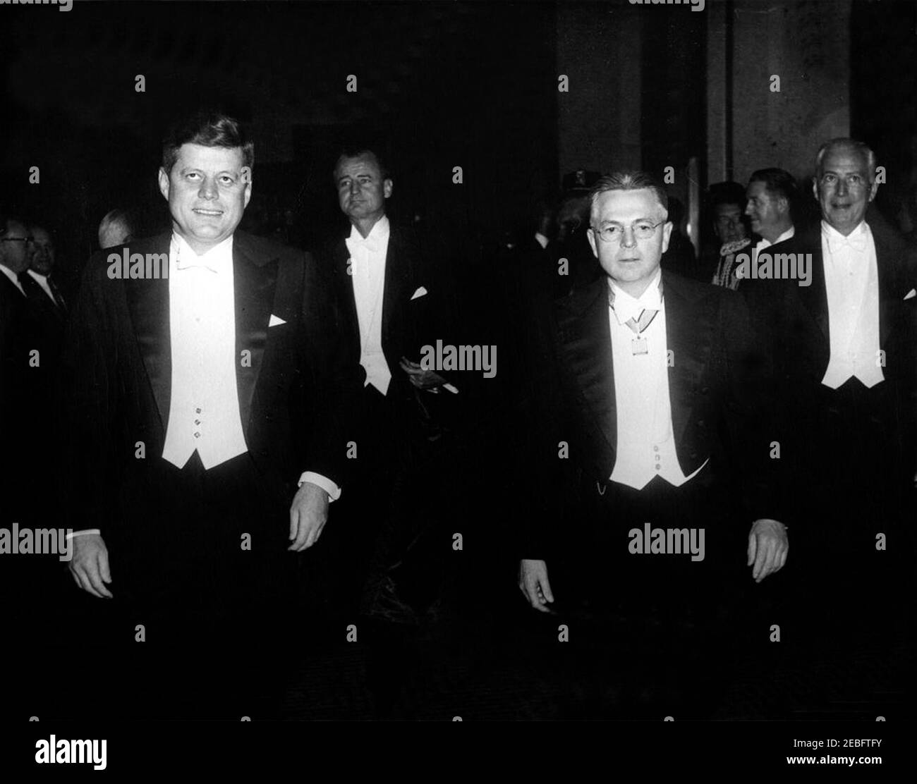 Cena al Gridiron Club, 18:54. Cena al Gridiron Club. Presidente John F. Kennedy; Senatore George Smathers (Florida); Presidente del Gridiron Club, Robert L. Riggs; Aide militare al Presidente, Brigadier Generale Chester V. Clifton (a ritroso, con la testa girata); Direttore Generale dello Statler Hilton Hotel, Herbert Blunck. Fuori dallo Statler Hilton Hotel, Washington, D.C.rnrn Foto Stock